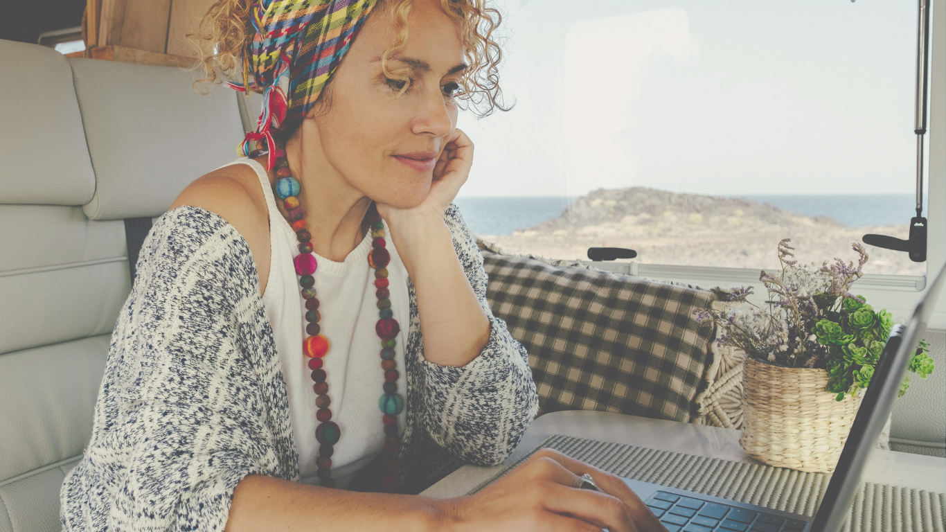 Middle aged woman using a laptop inside her RV, embracing full-time RV living and remote work on the road.